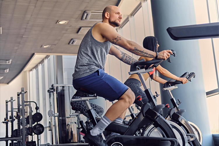 Male and two slim fitness female exercising with body bike in a gym